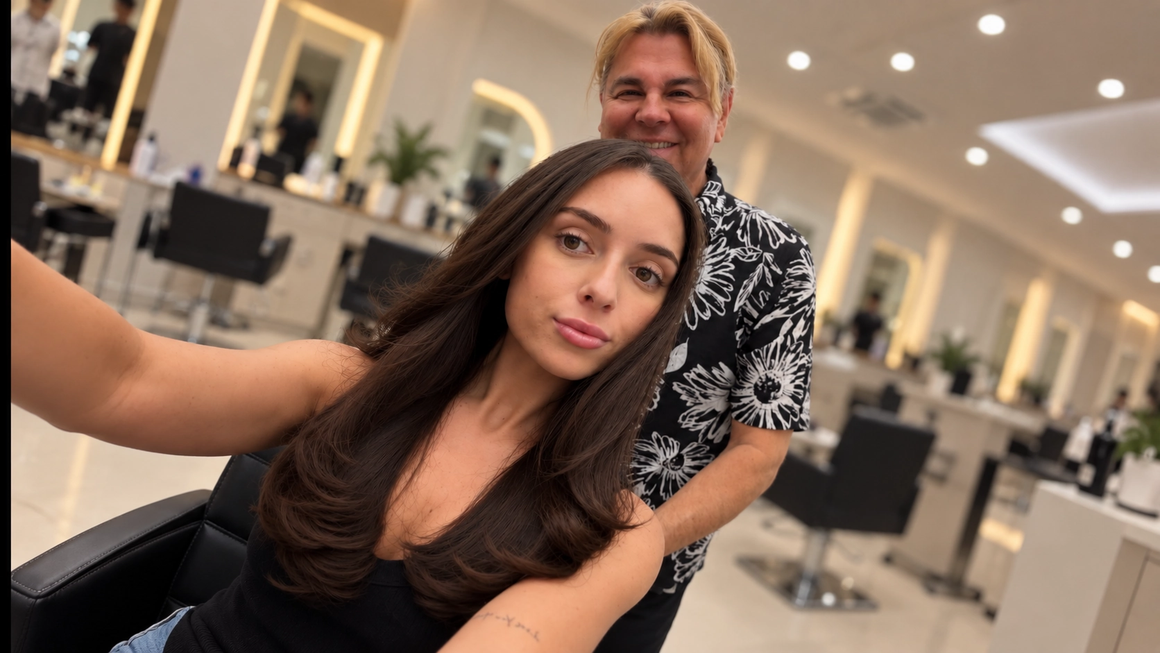 George Ivan Pena con una clienta de cabello castaño largo y brillante en el salón