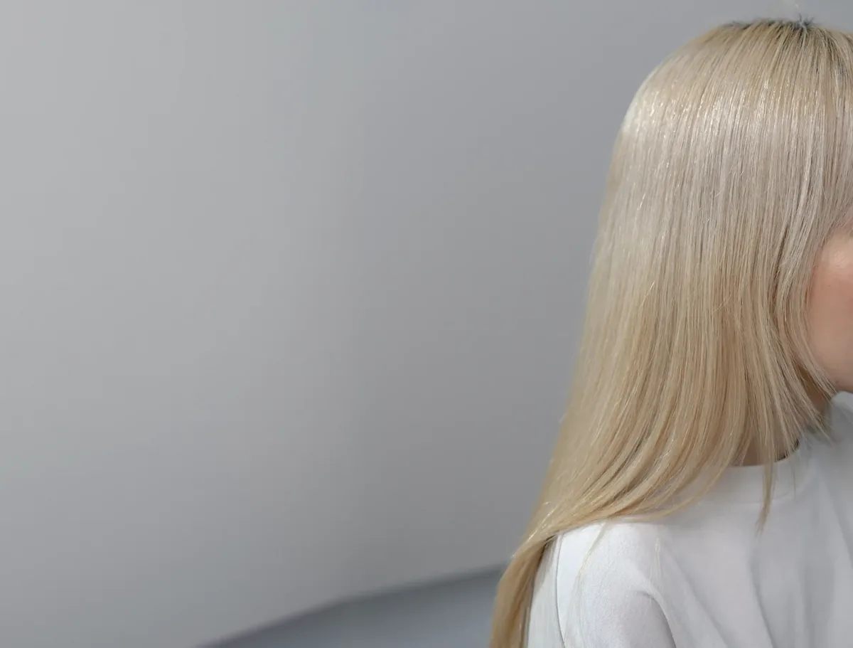 Una modelo de cabello platino largo y liso sobre un fondo gris de estudio